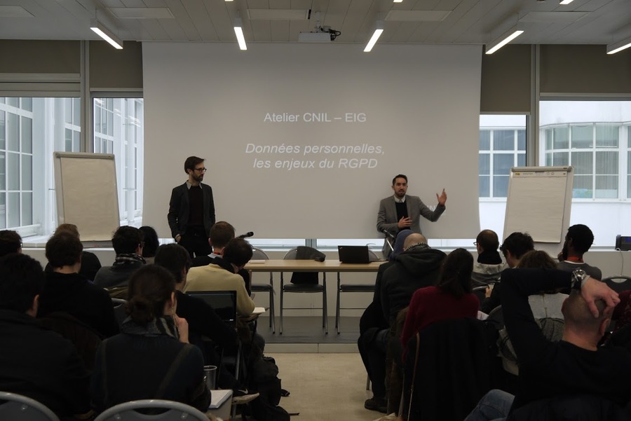 Deux hommes présentent devant un écran blanc où est projetée une présentation qui affiche “Atelier CNIL - EIG. Données personnelles, les enjeux du RGPD.